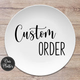 10 inch round white dinner plate with the text Custom Order in black. Custom is in a script font and order is in a skinny font. The logo for Our Platter is in the bottom left and background is a light brown wood.